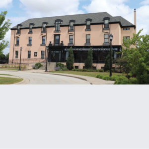 Historic brick building with modern glass extension under a blue sky.