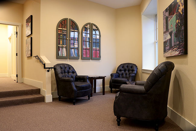 Cozy seating area with three black leather chairs and a small table.